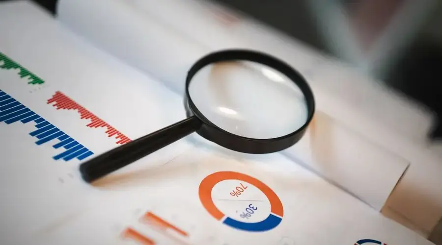 An image showcasing a magnifying glass placed on financial graphs and charts depicting statistical data.