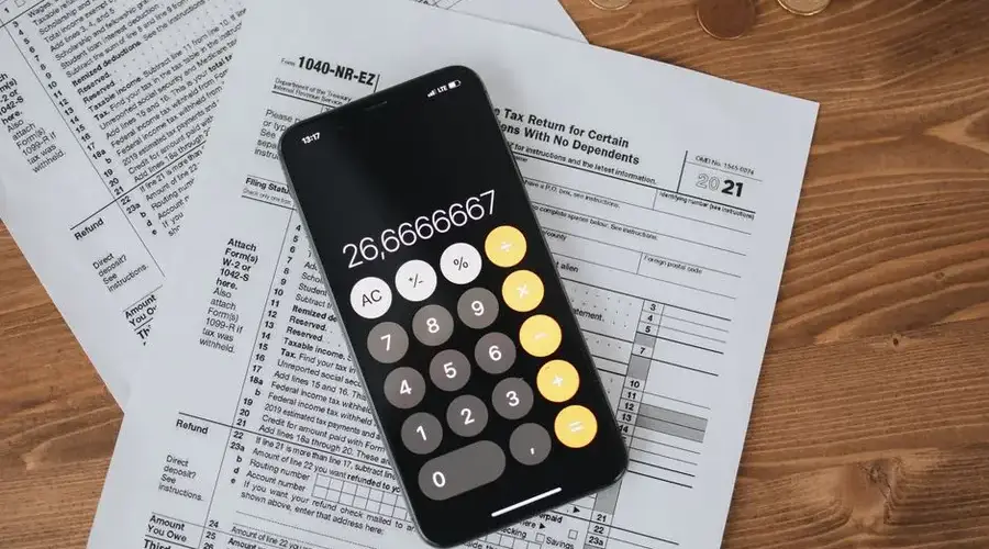 Overhead view of smartphone calculator on tax forms for finance and accounting.
