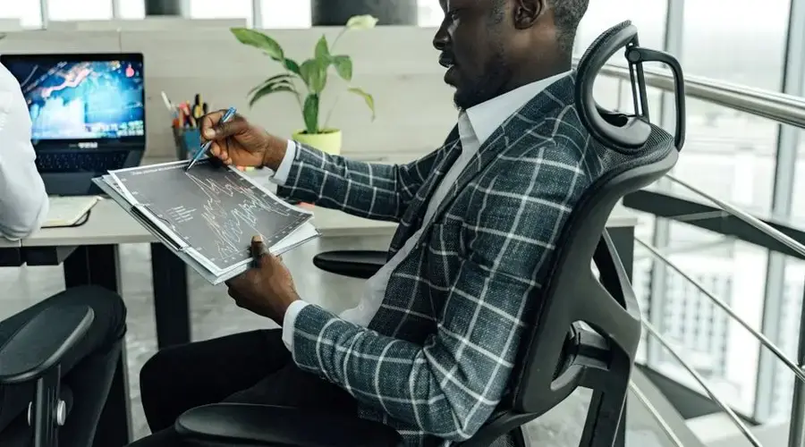 A businessman in a stylish suit reviews financial charts in a modern office setting.