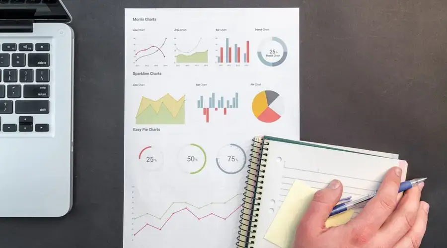Overhead view of a business desk with charts and a laptop, ideal for data analysis concepts.