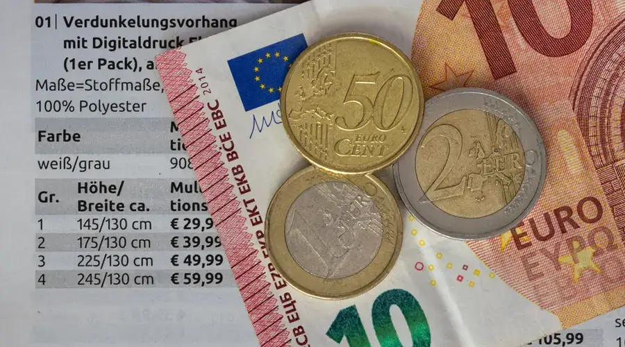 Euro coins and bills on a price list, symbolizing finance and economy.