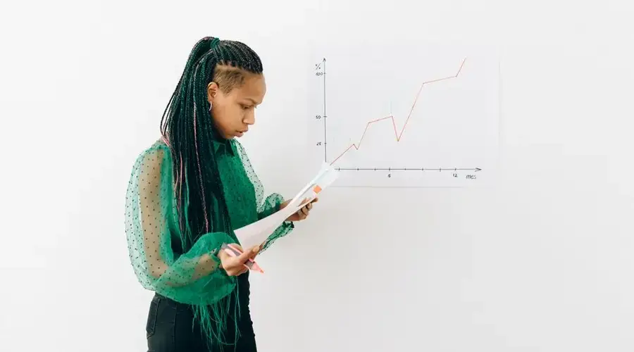 African American woman inspecting documents and graph charts indoors.