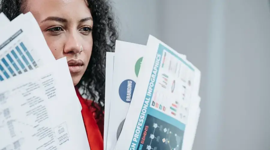 A businesswoman analyzing complex documents in a modern office setting.