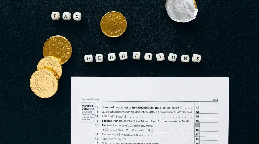 Image of tax deductions concept with coins and tax form on black background.