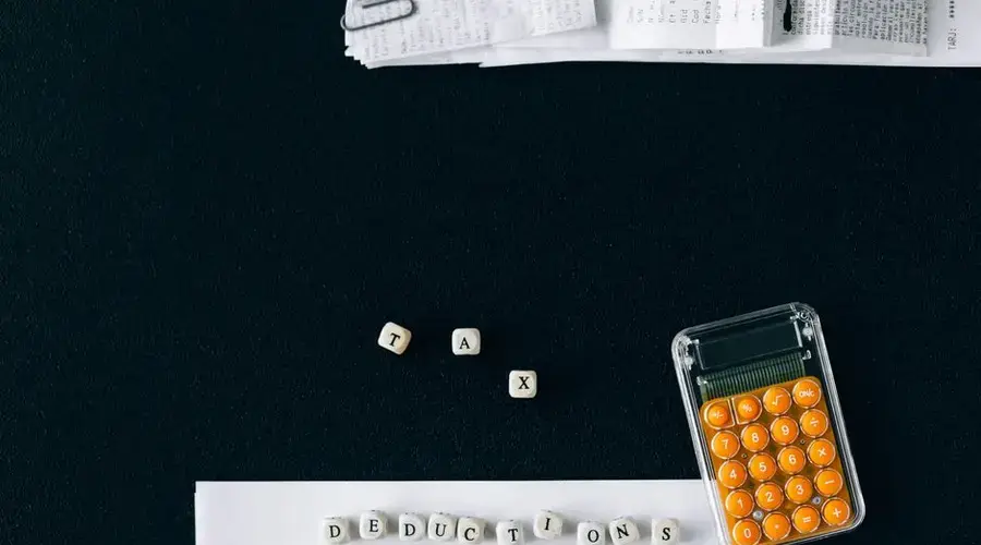 Top-down view of tax deduction items on a black background with a calculator and forms, emphasizing financial planning.