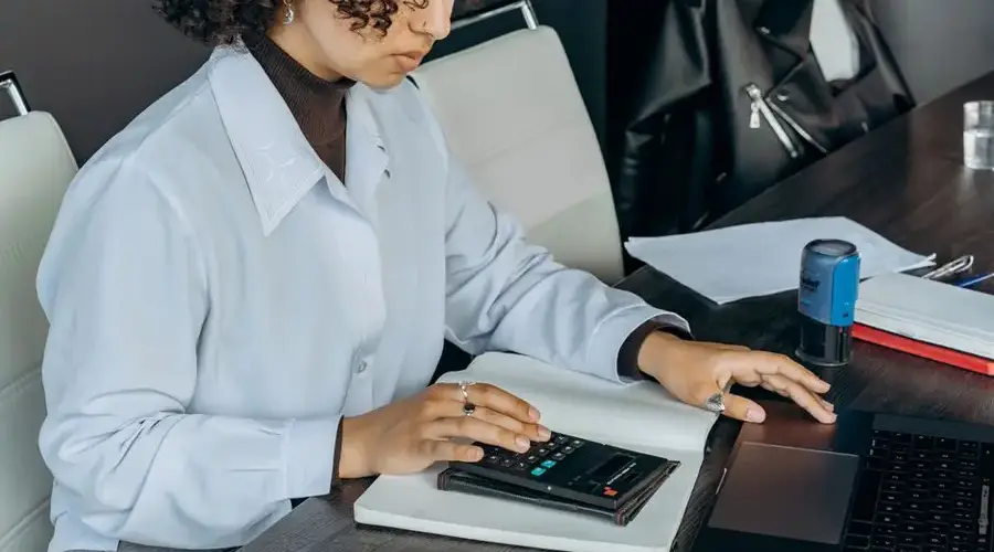 Young woman in office using a calculator for financial calculations.