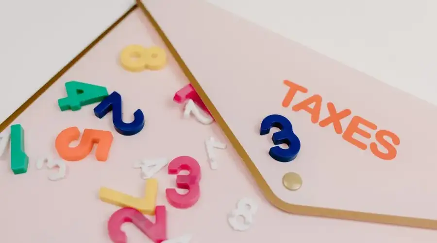 Bright plastic numbers scattered over a tax envelope, symbolizing accounting and finance concepts.
