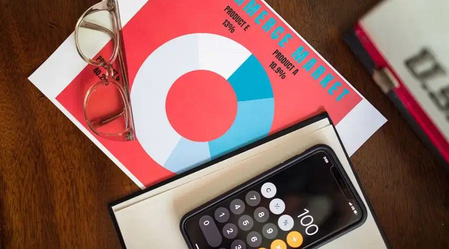 Top view of e-commerce market analysis graph with smartphone calculator and glasses for business insights.