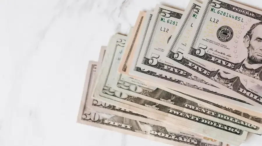Top view of stack of US dollar banknotes in different denominations on marble table