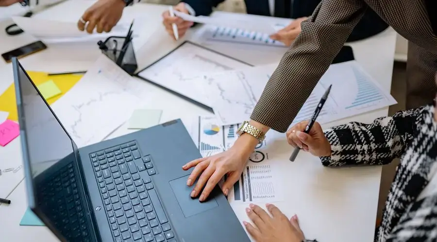 Business team analyzing data and charts during a meeting with a laptop on the table.
