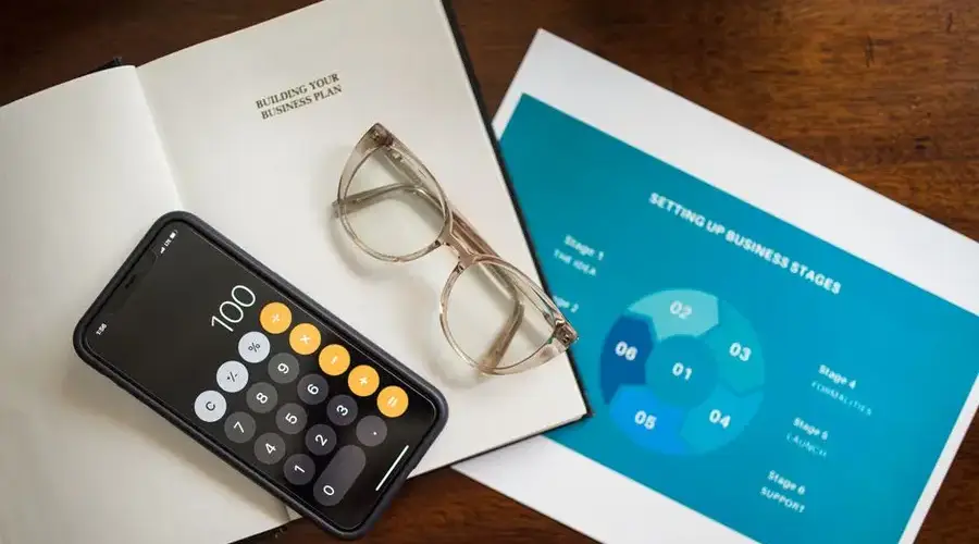 Open notebook, smartphone, and eyeglasses on a desk for business planning.