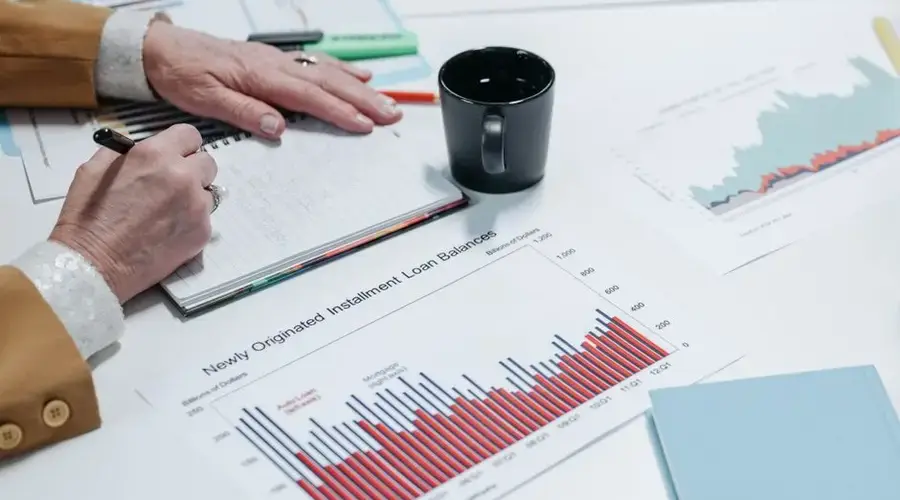 Close-up of a person analyzing financial charts and taking notes in an office setting.