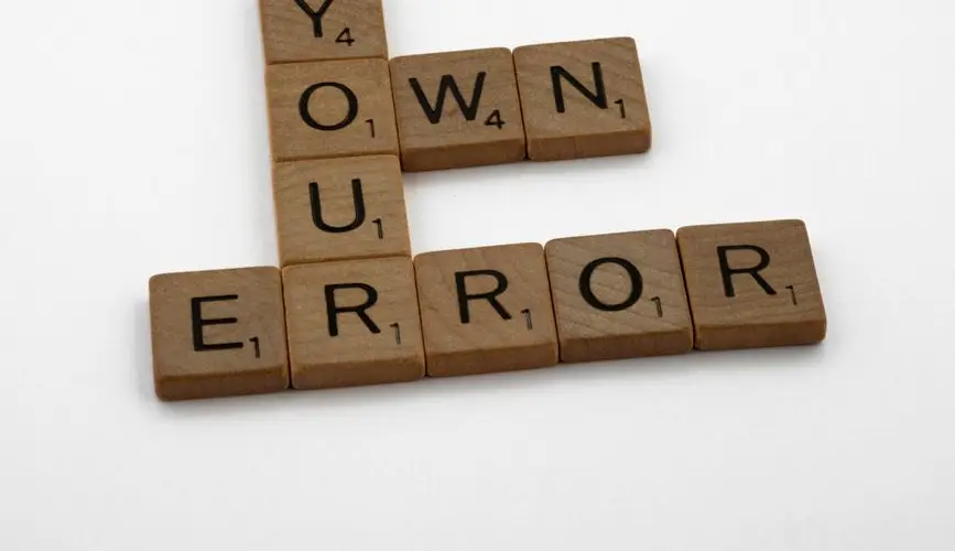 Scrabble tiles spelling 'Own Your Error' on a white background.