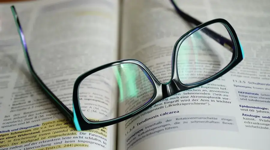 Reading glasses resting on an open book, symbolizing knowledge and learning.