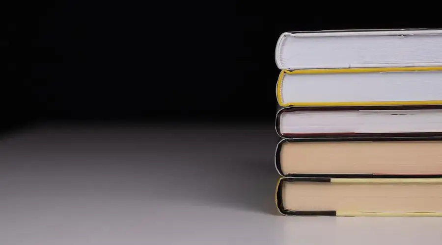 Minimalist stack of hardcover books with a black background and subtle lighting.