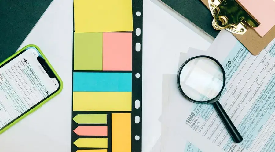 Colorful office supplies with smartphone and magnifying glass on tax forms. Perfect for business and financial themes.