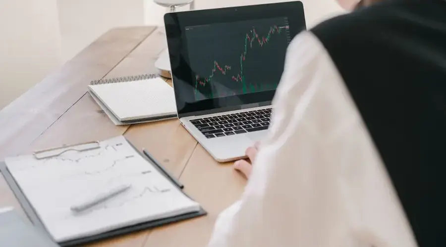 Business professional analyzing stock market trends on a laptop inside an office setting.