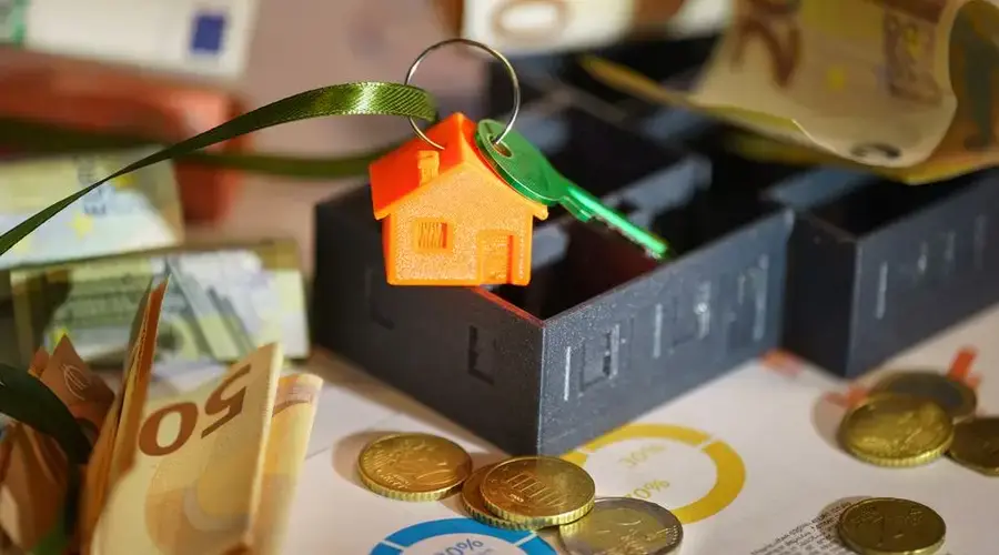 Image depicting real estate investment with keychain, euros, and financial charts.