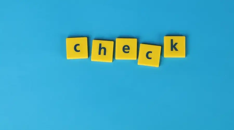 Yellow letter tiles spelling 'check' on a vibrant blue background, conveying approval or verification.