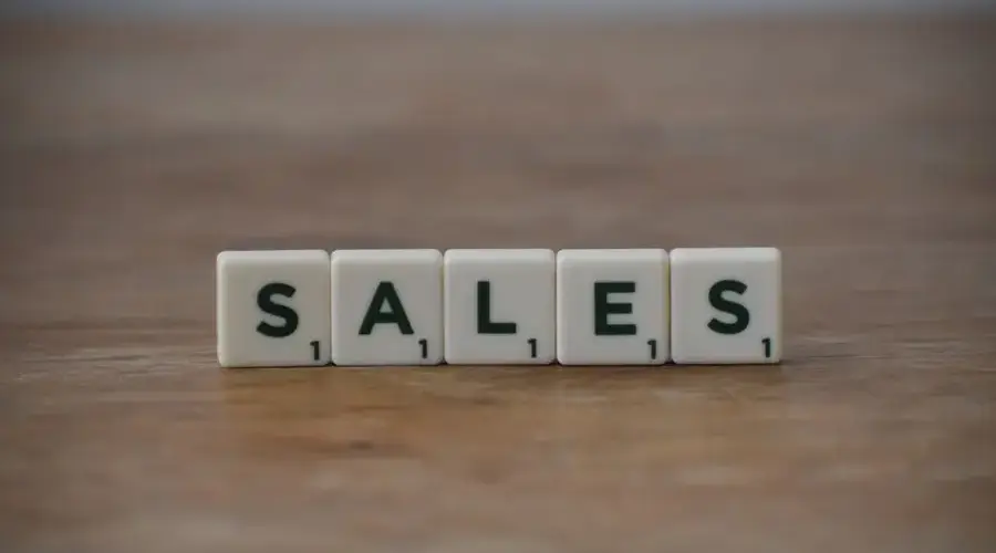Scrabble tiles spelling 'sales' on a wooden table, emphasizing business and marketing.