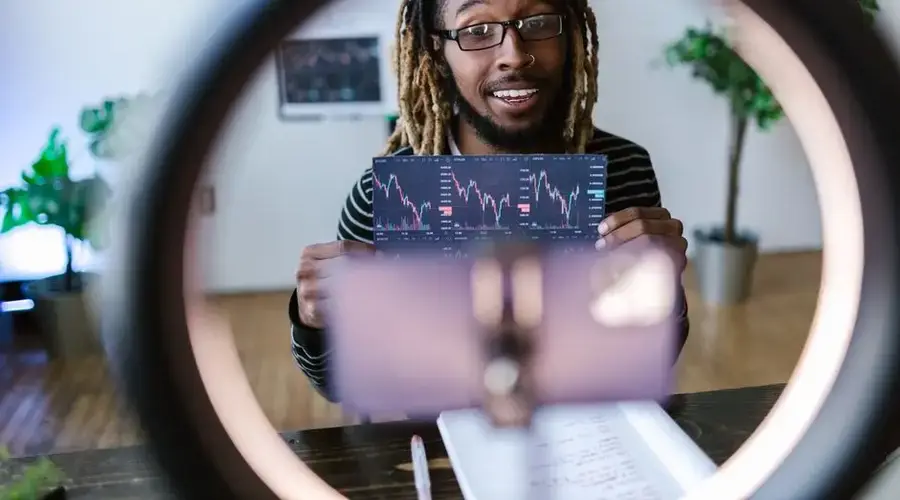 A man holds a cryptocurrency chart indoors, highlighting investment trends.