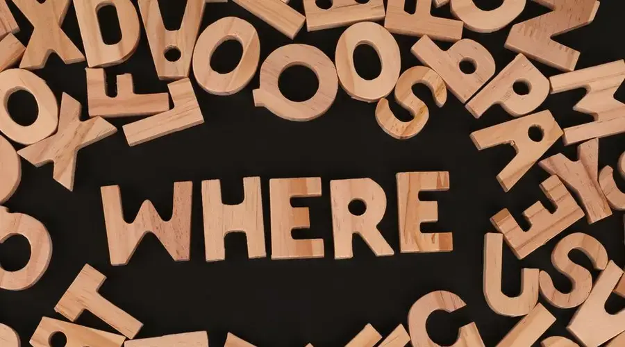 Wooden letters on black background spelling 'WHERE', showcasing typography design.