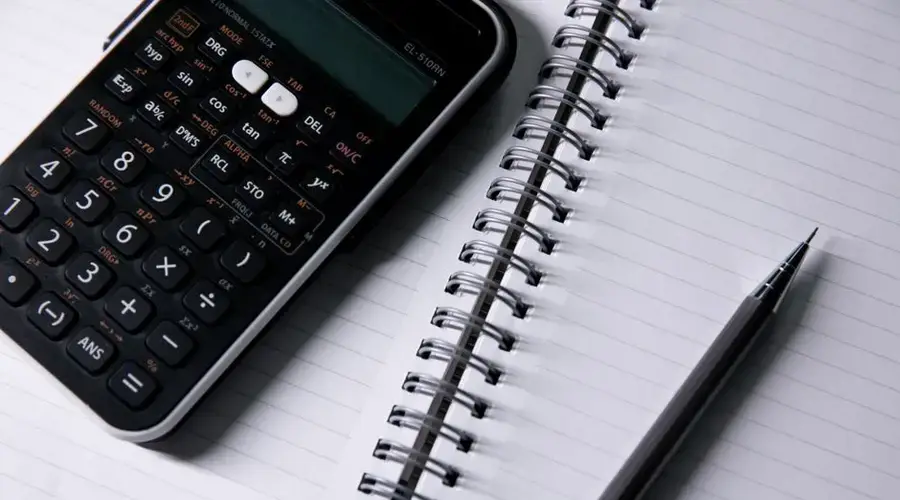 Close-up of a calculator and open notebook with a pen on a desk, ideal for office or school themes.
