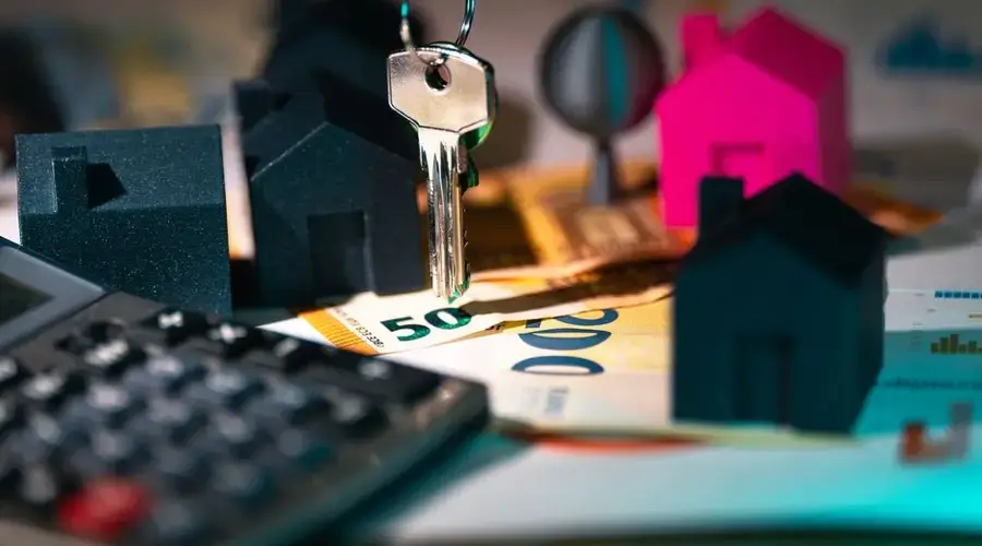 A symbolic representation of real estate finance featuring keys, model houses, and euro banknotes.