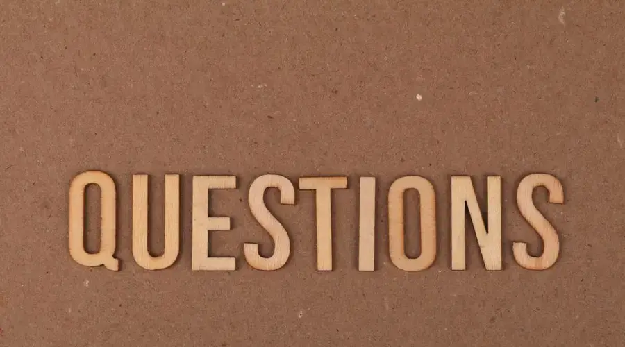 Wooden letters spelling the word "QUESTIONS" on a cardboard background, providing a neutral copyspace.