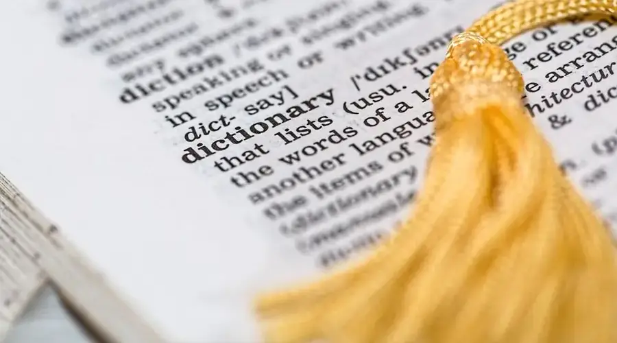 Close-up image of a dictionary page focused on the word 'dictionary' with a yellow tassel.