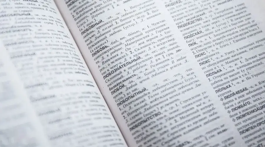 Close-up view of an open Russian dictionary showing detailed text and entries.