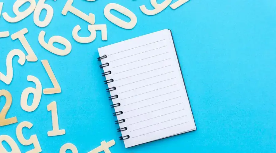 Top view of blank notebook with scattered numbers on a vibrant blue background.