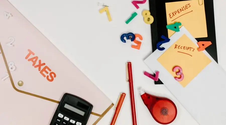 Flat lay of tax documents, receipts, calculator, and colorful numbers for budgeting.