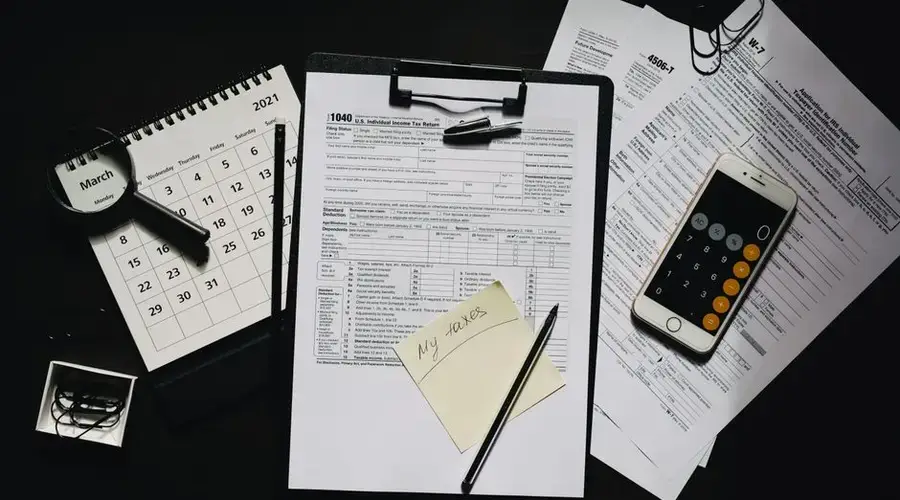 High angle view of tax forms, calculator, calendar, and pen for financial planning.
