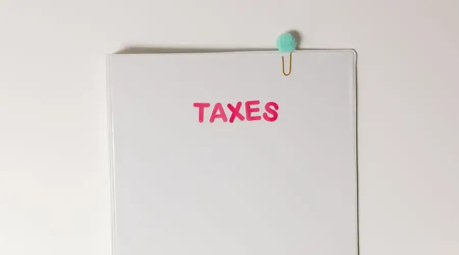Close-up of a tax file with a pink 'TAXES' label and a paperclip, offering copy space and a conceptual minimalist design.