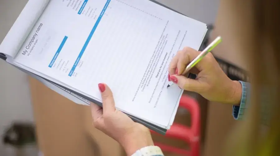 Close-up of woman's hand signing a document on a clipboard. Ideal for business and legal themes.