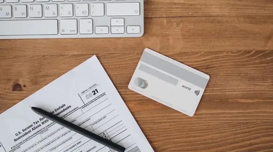 Overhead view of a desk with tax form, pen, keyboard, and contactless card.