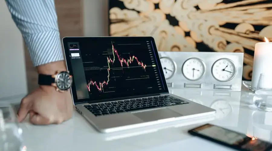Modern office setup featuring a laptop and world clock, ideal for finance or trading.