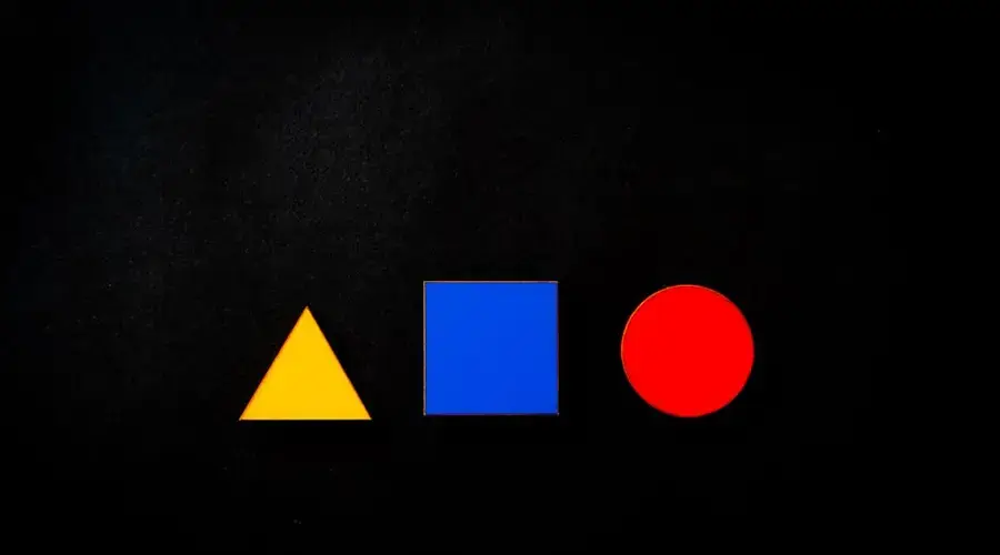 Vivid geometric shapes of triangle, square, and circle in primary colors on a black background.