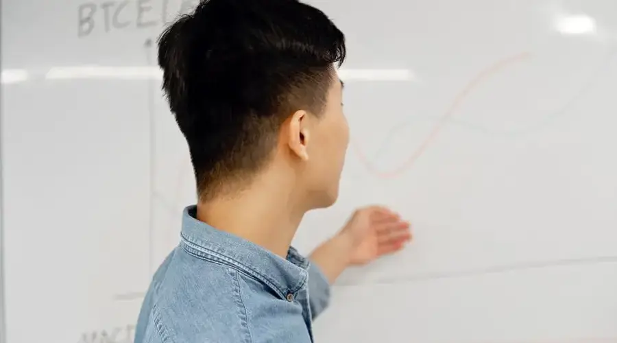 Man presenting business data analysis on a whiteboard indoors.