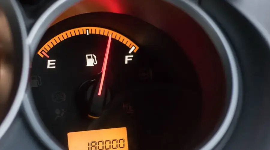 Close-up image of a car's fuel gauge showing a full tank with an odometer reading of 180000 miles.