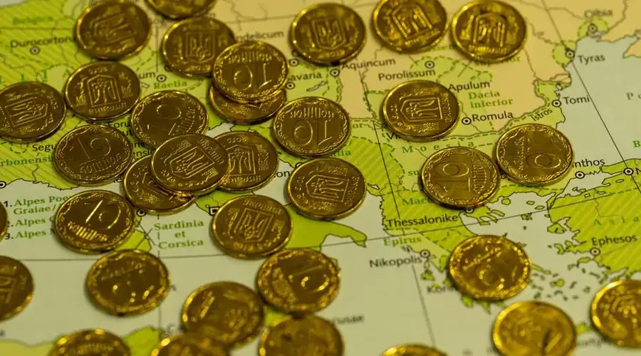 Pile of gold coins placed on top of a detailed geographical map.