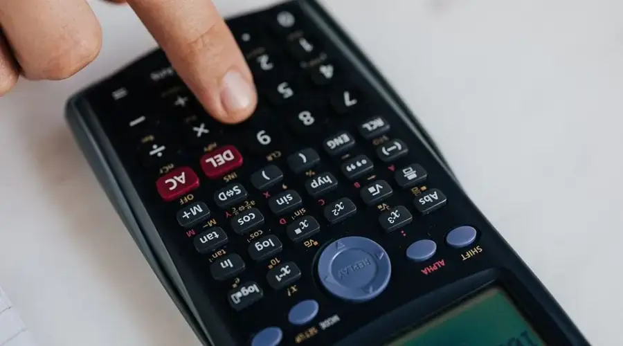 From above of crop anonymous economist calculating on calculator with plastic buttons while making budget on marble table