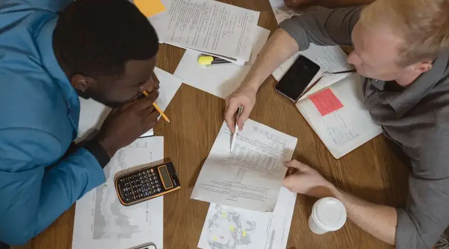Two professionals engaged in a teamwork meeting, discussing documents and finance.