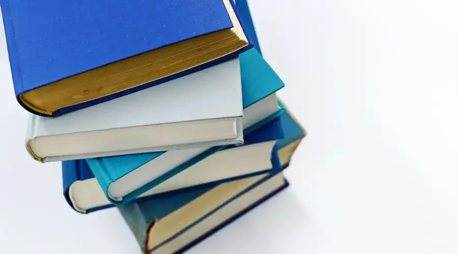 A vertical stack of books with blue covers on a white background symbolizes education and literature.