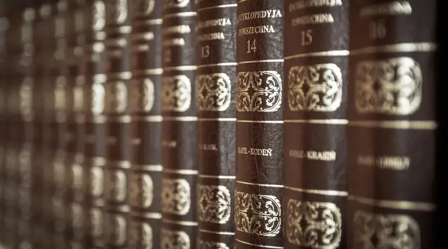 A close-up view of vintage encyclopedias on a library bookshelf, highlighting the ornate leather bindings.