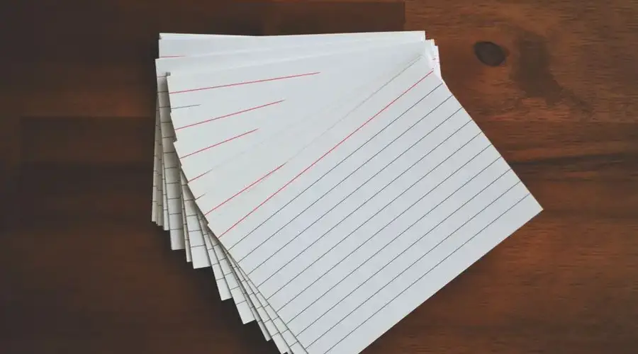 High-angle view of blank index cards arranged neatly on a wooden desk, ideal for education and organization concepts.