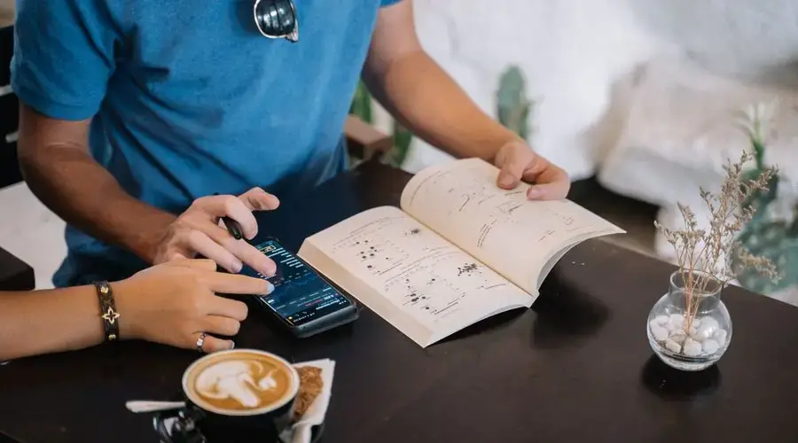 Two people enjoying coffee and reading in a cozy café setting, relaxing vibes.