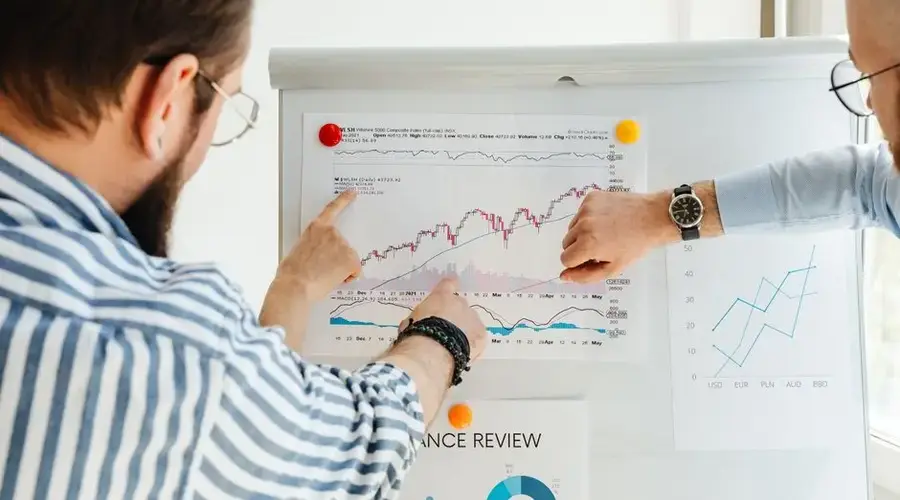 Colleagues discussing data trends on a whiteboard with graphs and charts.