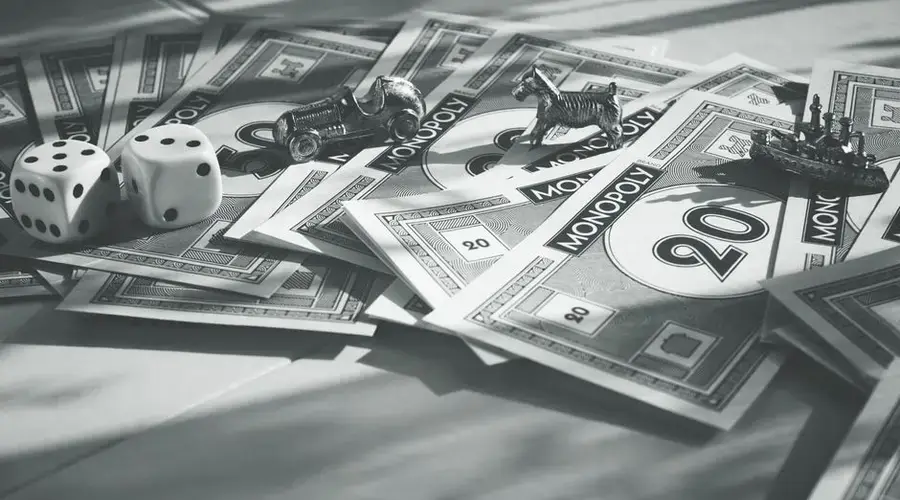 A close-up of monopoly money, dice, and game pieces in monochrome color scheme.